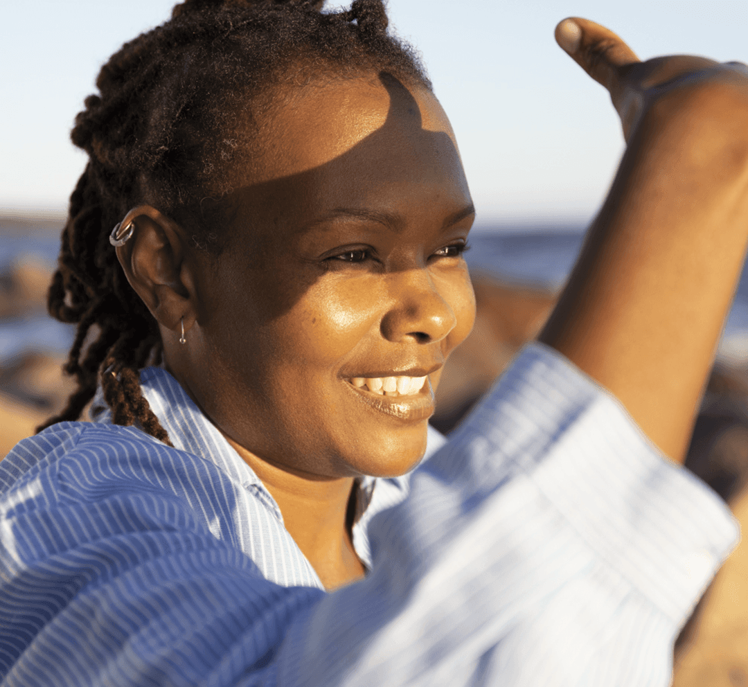 A woman smiling in the sun by the sea